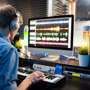 Young,Musician,With,Headphones,Pressing,Keys,Of,Piano,Keyboard,While